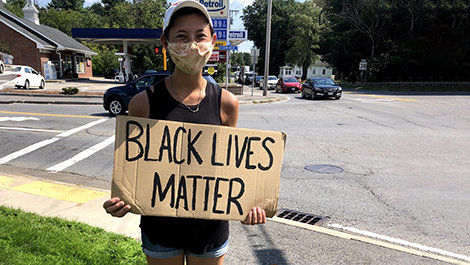 Jasmine Won holds a Black Lives Matter sign beside a road.