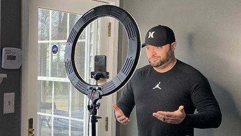 Keith Gilchrist records a TikTok video using a ring light.