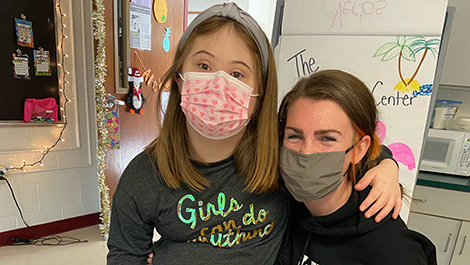 Nikki Maloney poses for a photo in a classroom with a student.