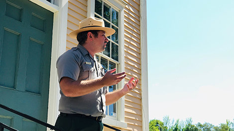 Mark Mello speaks while standing in front of a historic building.