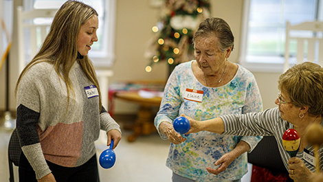 A student and seniors shake maracas.