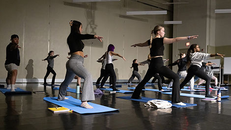 Students twist their bodies and extend their arms during a yoga exercise.