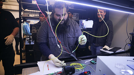 Samuel Bechtold works with wires in a photonics lab.