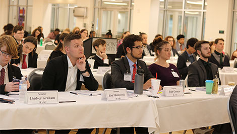 Students portraying senators sit behind tables arranged in rows.