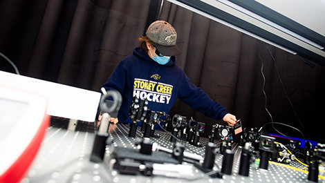 Peyton Brown adjusts photonics instruments mounted to a lab table