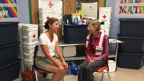 Maggie Lowe, wearing a Red Cross vest, talks with a flood victim.