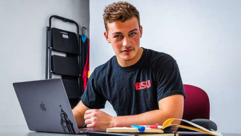 Ryan Kuczer sits at a desk working on a laptop