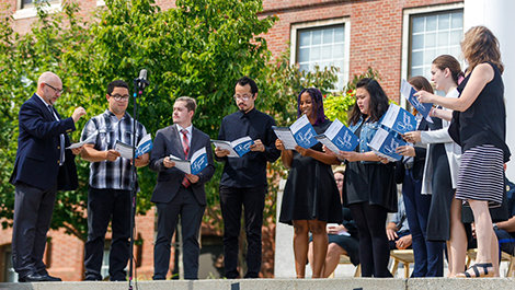Nine members of the Social Justice Choir sing while standing on concrete steps.