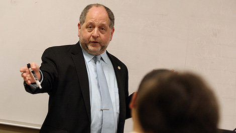 Aeon Skoble lectures in front of a white board while holding a marker.