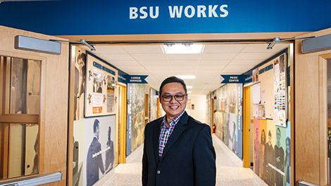 Gerald Tang stands in a hallway below a BSU Works sign