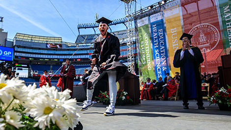 A student shows excitement as he crosses the commencement stage.