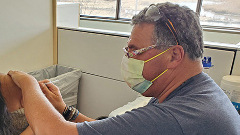 Chris Greim administers a vaccination.