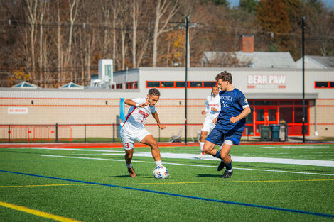 3 soccer players playing on Mazzafero field with the Bear Paw Pavilion behind them