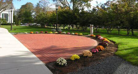 a photo of a half circle of bricks next to Boyden Hall surrounded by flowers