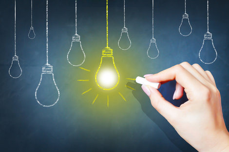A person draws a lightbulb on a chalkboard (photo illustrati A person draws a lightbulb on a chalkboard (photo illustrati