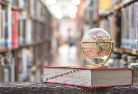 A globe sits on a book in a library A globe sits on a book in a library