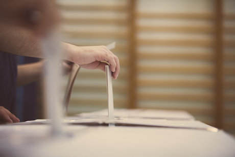 A hand puts a ballot in the ballot box A hand puts a ballot in the ballot box