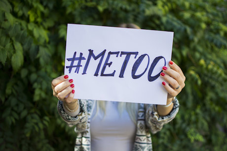 A woman holds up a sign that says "#metoo" A woman holds up a sign that says "#metoo"