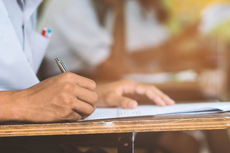 A student’s hands are pictured as he takes a written exam A student’s hands are pictured as he takes a written exam