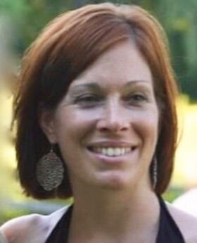 Audra Carabetta smiling with medium length reddish brown hair wearing a black halter top