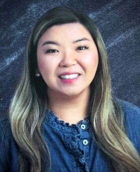 Melissa Cieto smiling with long dark hair with highlights and wearing a blue button up collarless top