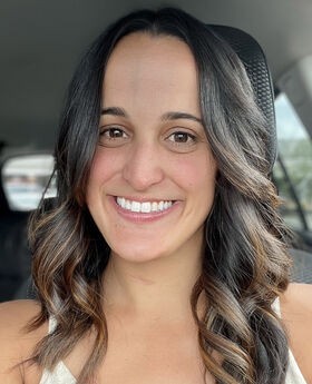 Anabel Graham smiling with long brown hair and wearing a v-neck sleeveless top