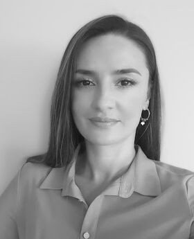 a black and white photo of Dr. Albulene Kastrati. She has long straight dark brown hair and is wearing a button up collared blouse