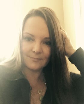 Jodie Drapal Kluver with long straight brown hair wearing a dark colored long sleeve zipper neck top