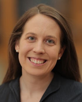 Dr. Caitlin Martinez smiling with long brown hair and wearing a v-neck black top
