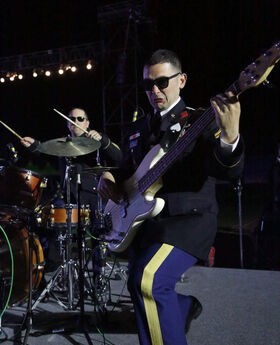 Nick Rice playing bass guitar on stage with the US Army Band