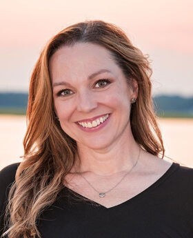 Wendy Rockne smiling with long brown hair and wearing a black v-neck top