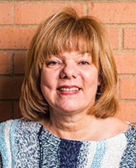 headshot photo of Christine Rowan with medium length light brown hair wearing vertically striped blue and white sweater