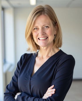 Dr. Melissa Winchell smiling with medium length dirty blonde hair and wearing a navy blue top