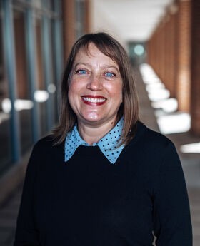 Dr. Jennifer Winters smiling with medium length brown hair and wearing a light blue polka dot collared top under a navy blue sweater