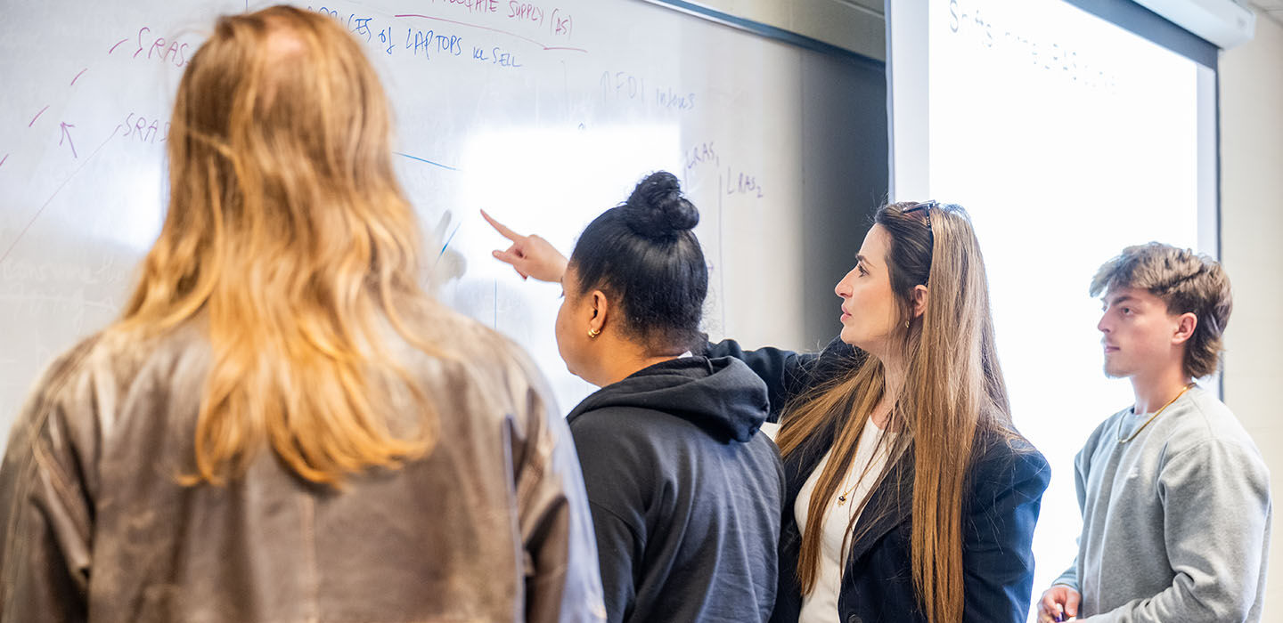BSU Professor Abuelene Kastrati helps students working on a white board