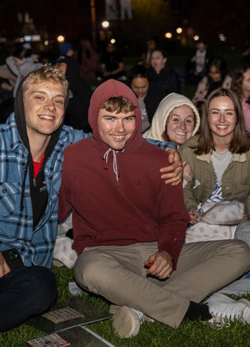Four students smile, with their arms around each other, at Big A Bingo on the Boyden lawn