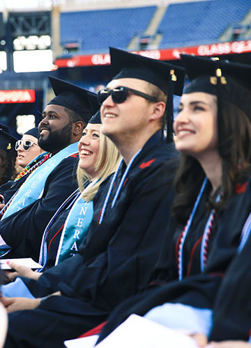 A row of smiling graduates at 2023 commencement