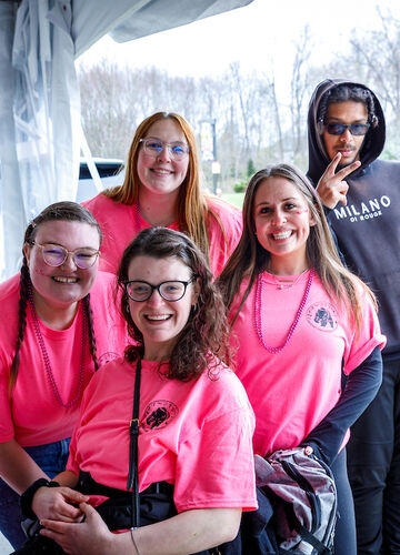 a group of 5 students smiling at the camera with University Park in the background. Four are wearing Student Accessibility Services t-shirts