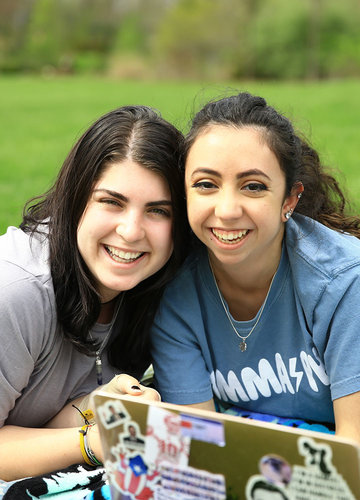 Two students studying outside and smiling at the camera