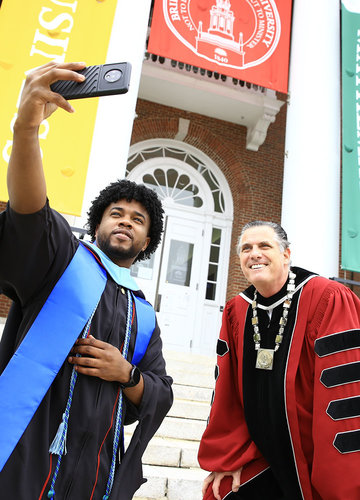 A 2021 graduate taking a selfie with President Clark on the steps of Boyden Hall